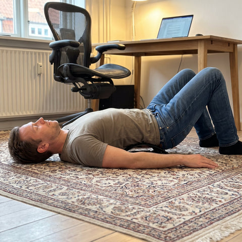 Mand ligger på BackStretcher Pro rygstrækker på gulvet efter en dag ved skrivebordet