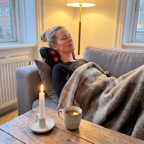 MusclePillow trådløs massagepude bag nakken i sofaen